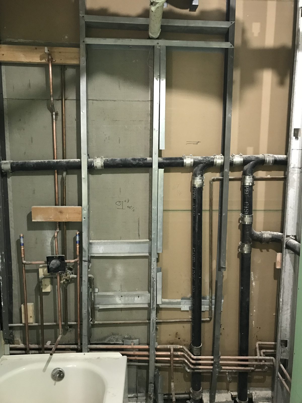 Bathroom rough-in: supply and drain lines behind the tub before the walls close